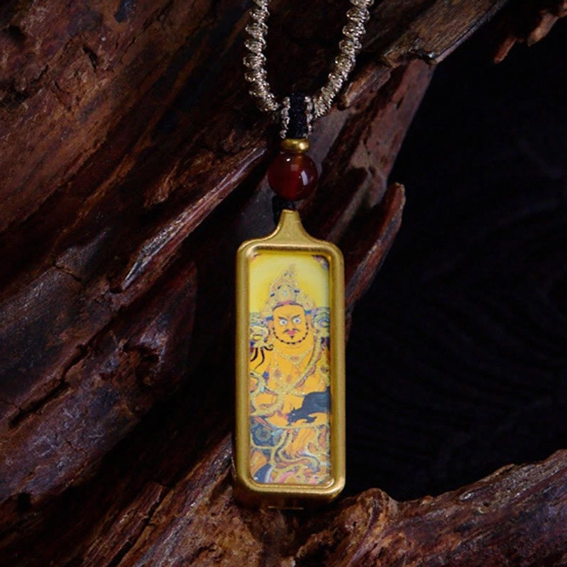 Yellow Zambhala wealth deity Tibetan thangka hand-painted pendant necklace with gold frame and red agate bead, close-up front view