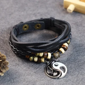 Black yin yang leather bracelet with silver pendant and wooden beads on natural tabletop