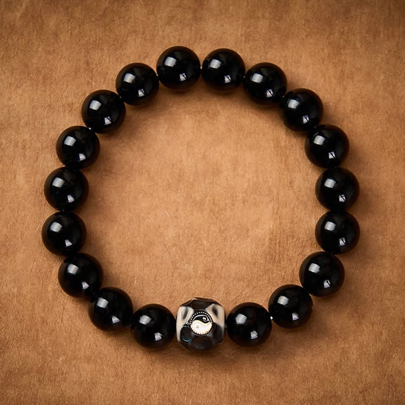 Tibetan Yin Yang harmony bracelet featuring smooth black obsidian beads and faceted accent bead
