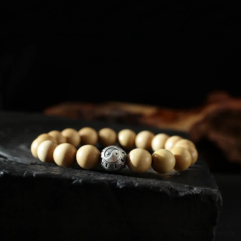Yin yang symbol peach wood bracelet - natural wooden beads with silver-tone spacer on dark platform