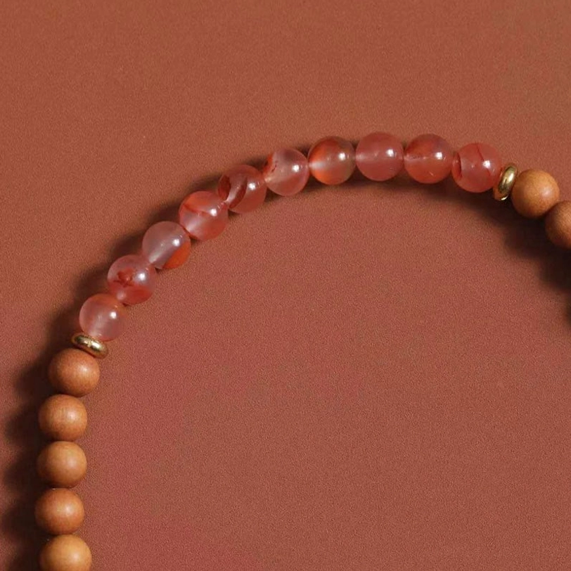 Close-up detail of Zakiram bracelet featuring icy-sky veined South Red Agate beads, sandalwood spacers, and metal accents