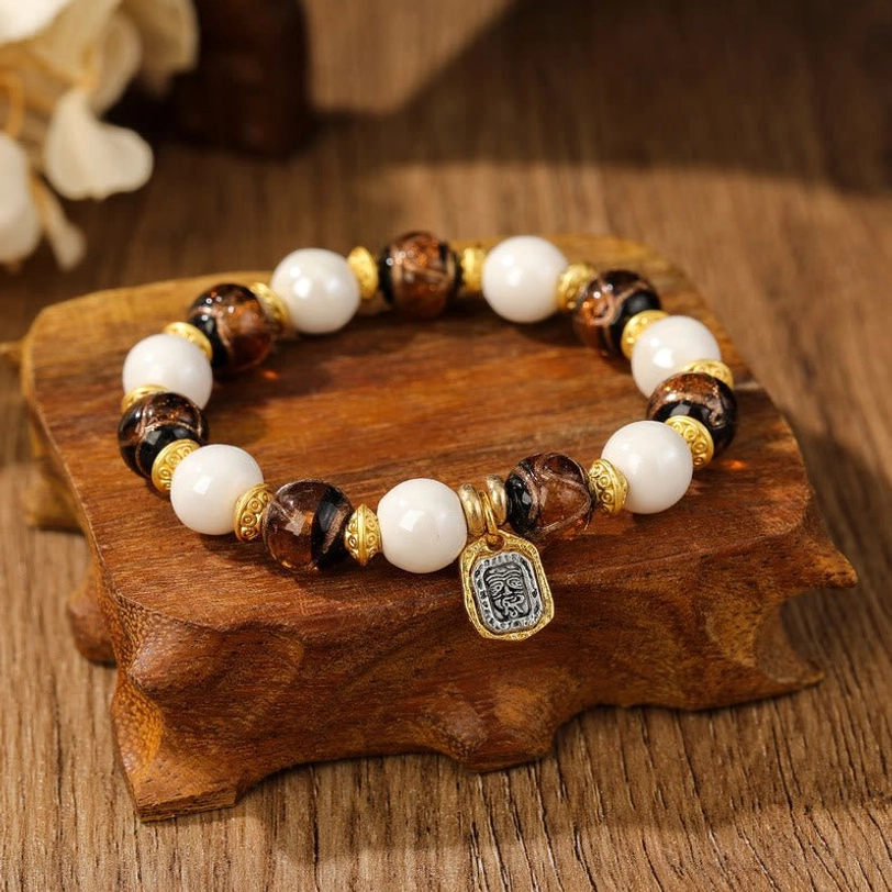 Dark brown Tibetan Zakiram bracelet with white beads and brown glazed liuli glass on wooden tray