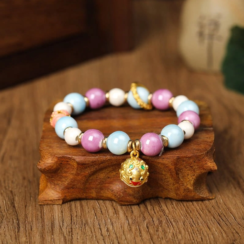 Zakiram Goddess wealth bracelet with gilded hollow sphere charm and incense ash porcelain beads, overhead flat view