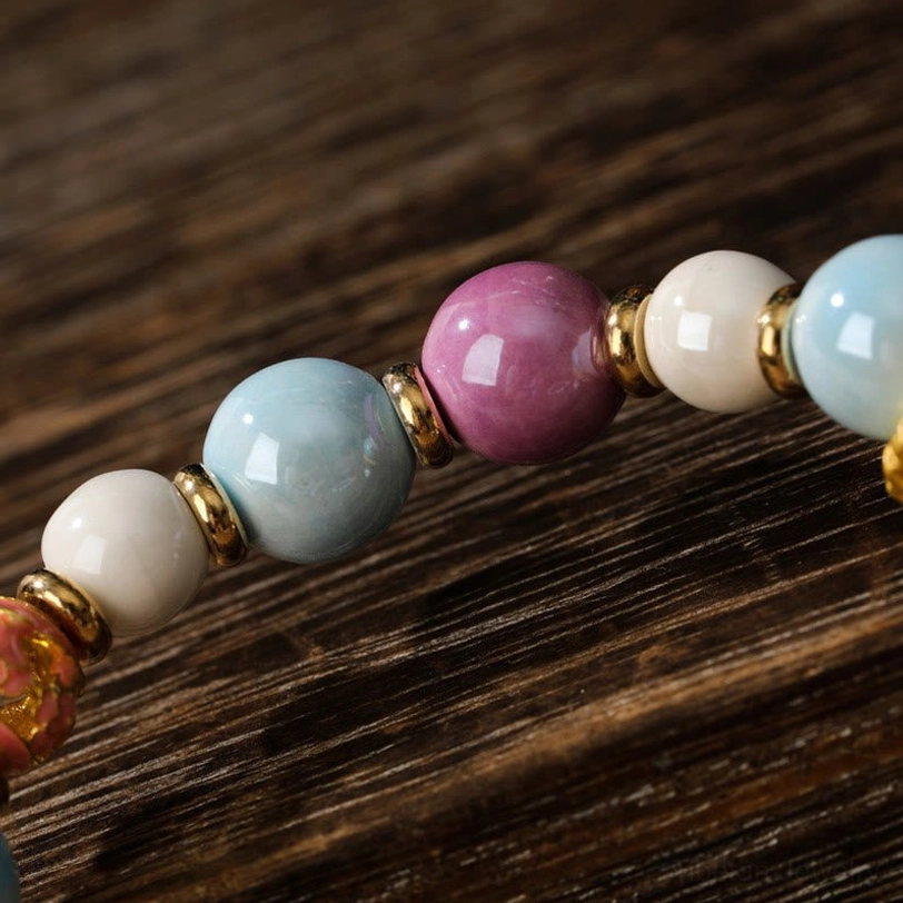 Macro photography of Zakiram Goddess bracelet with round liuli glass beads in pastel colors connected by gold-toned metal spacers