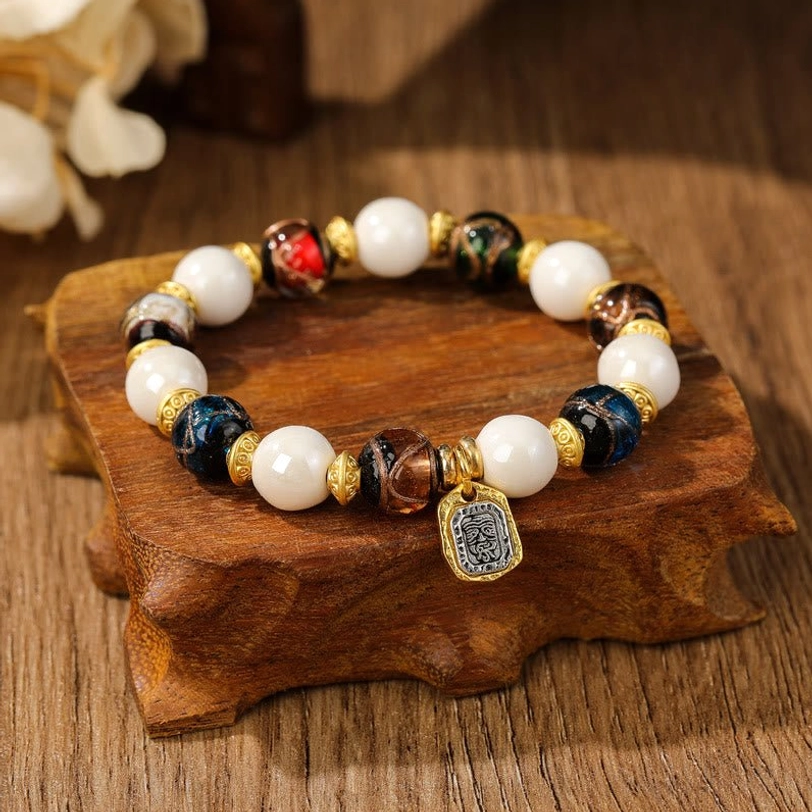 Blue-brown Tibetan Zakiram charm bracelet with white beads and multicolored glazed glass on display