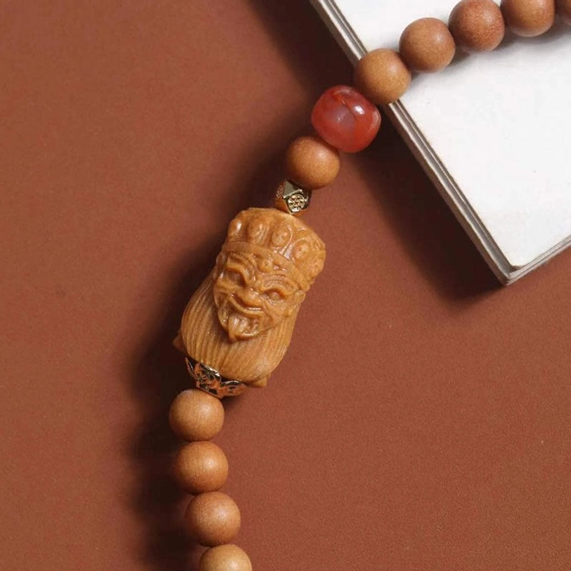 Intricate carved sandalwood Zakiram deity pendant with inlaid blue and red decorative accents, spiritual protection symbol
