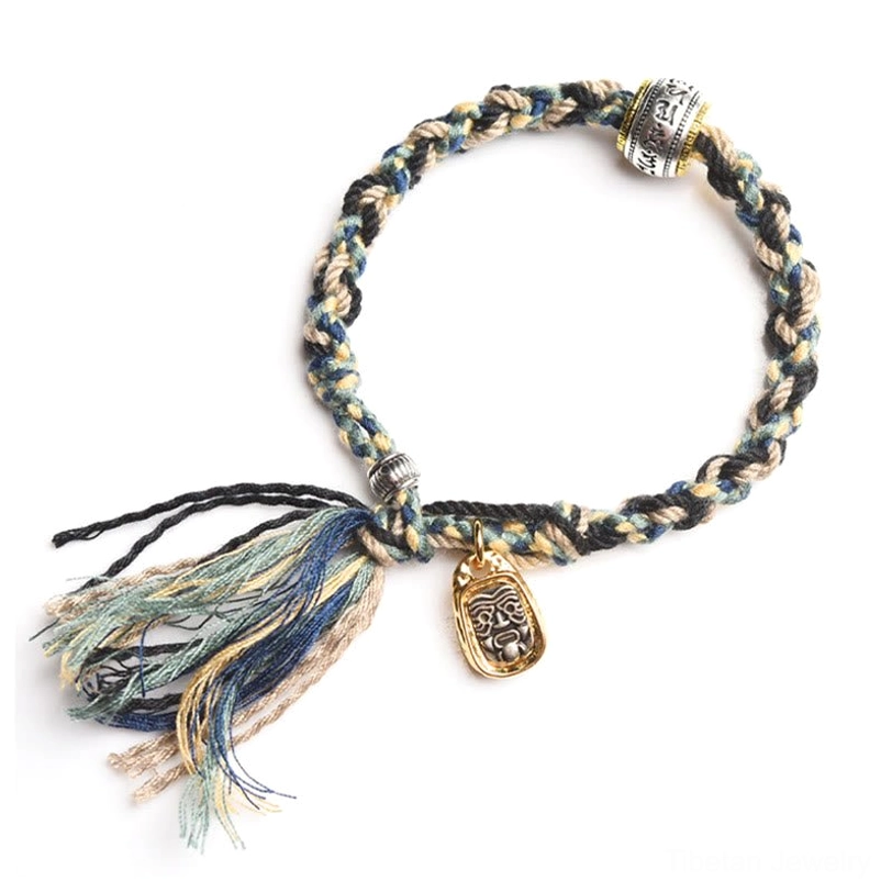 Dark blue black Tibetan Zakiram goddess bracelet with frayed tassels gold pendant and silver hardware on white background