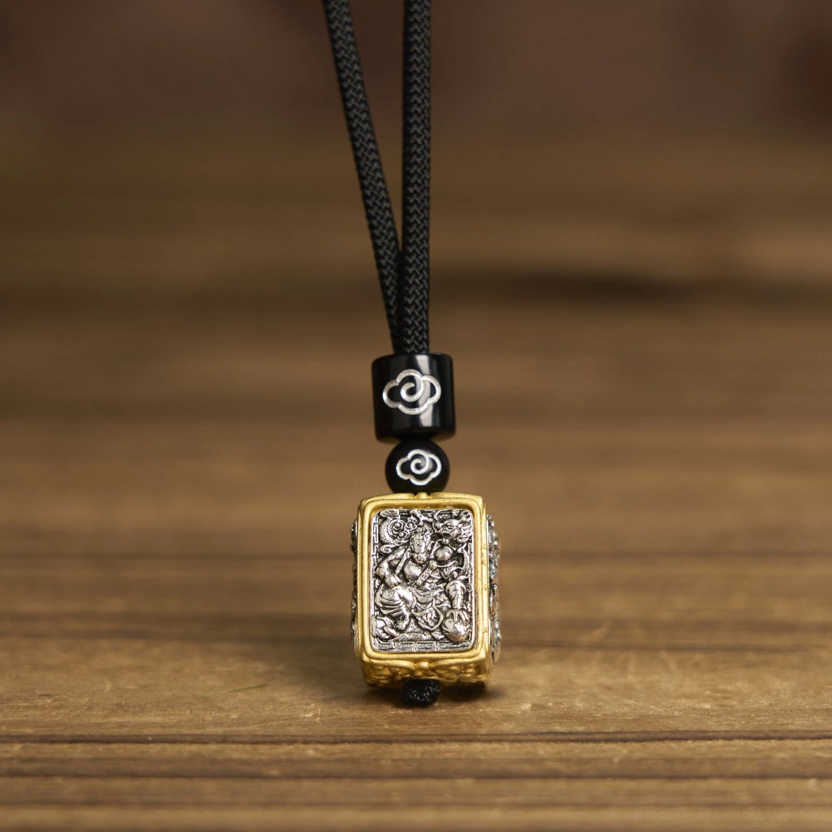 Zakiram goddess of wealth tibetan deity pendant necklace front flat lay, showing black braided cord, cloud-patterned decorative beads, and square relief pendant with gold-silver finish