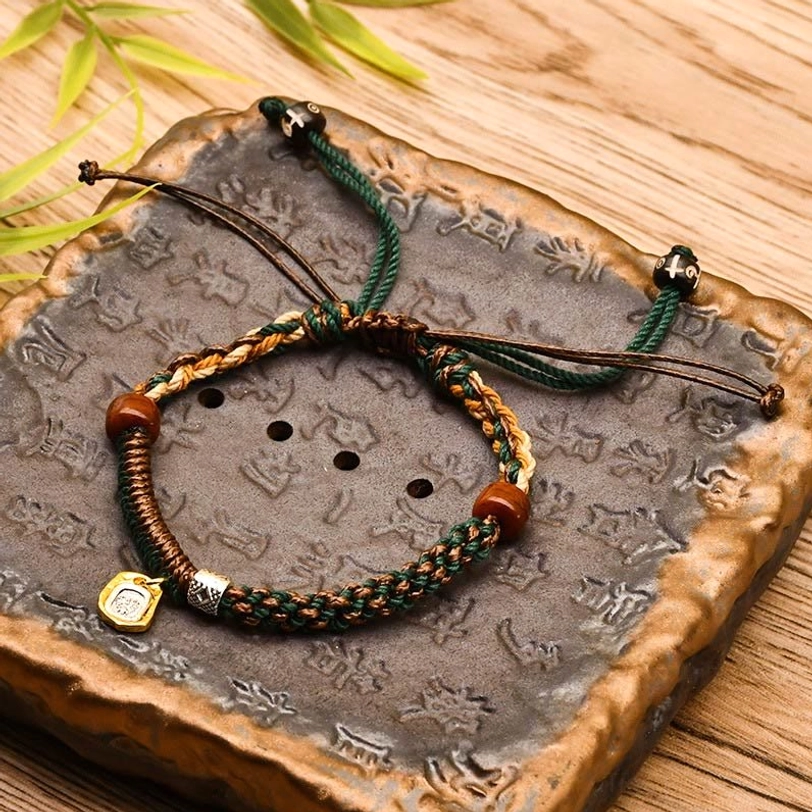 Green Zakiram tibetan bracelet with mixed woven cords, wooden beads, and dual-tone metal accents on vintage carved stone