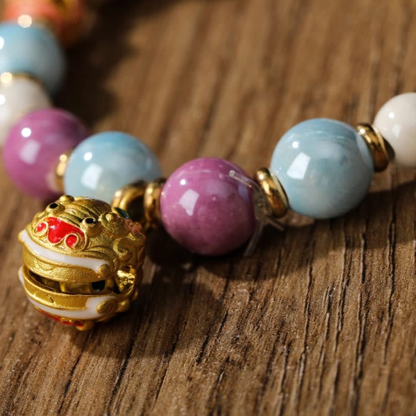 Close-up of Zakiram Goddess bracelet featuring gold-toned lion head charm with enamel details and liuli glass beads