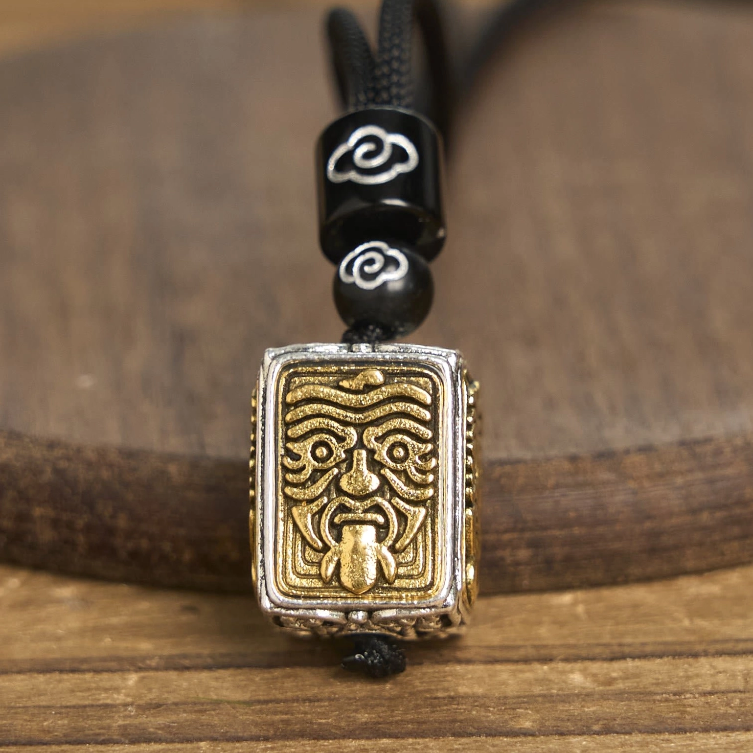 Zakiram goddess of wealth tibetan square pendant necklace close-up detail shot, showing cloud-patterned black beads and bicolor relief pendant with braided rope