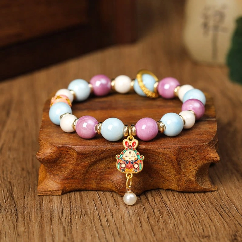 Single Zakiram Goddess wealth bracelet featuring enamel rabbit head charm with liuli glass beads, front flat view on wooden stand