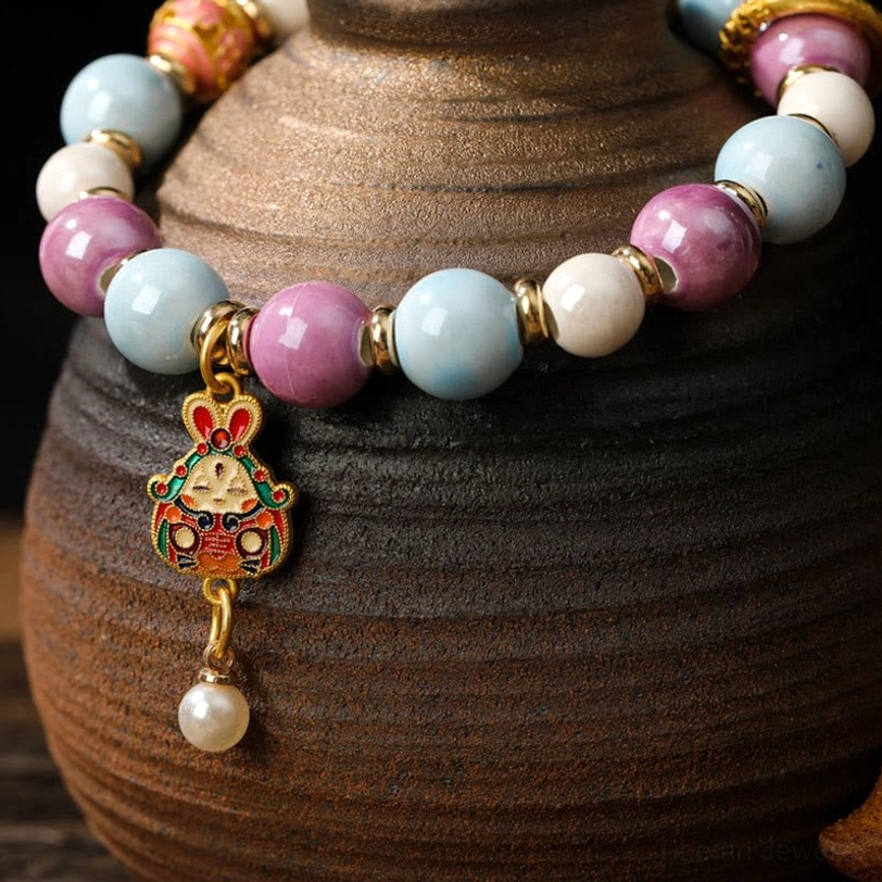 Close-up detail of Zakiram Goddess bracelet with enamel rabbit charm and pastel liuli glass beads, side view