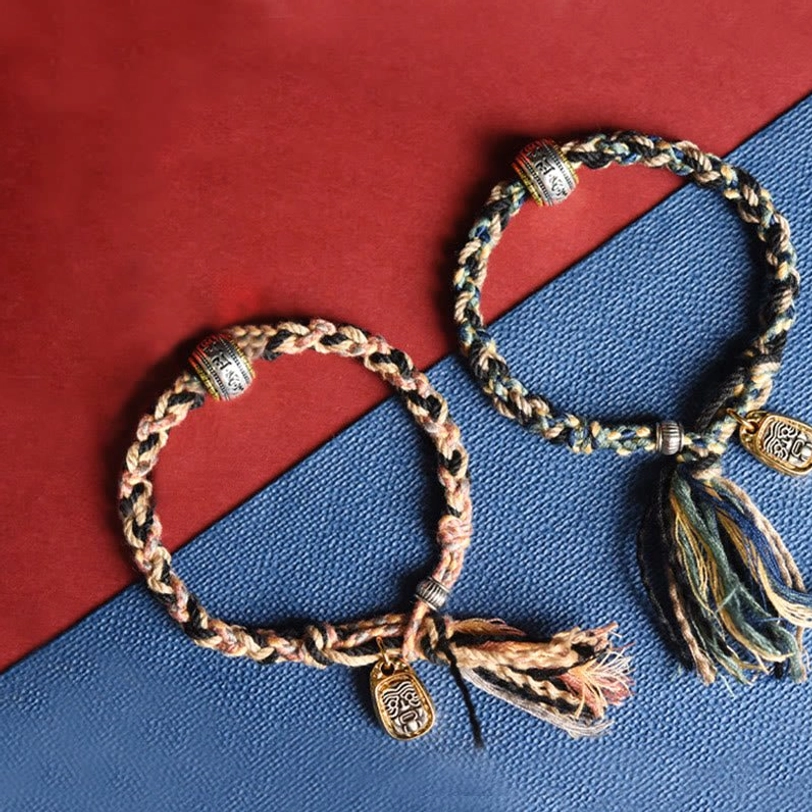 Matching pair of Tibetan Zakiram goddess bracelets one dark mixed cord one tan cord both with gold pendants and tassel frays
