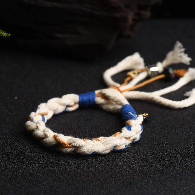 Handmade Tibetan Zakiram bracelet with tri-color woven pattern, simple tassel, and copper charm accents