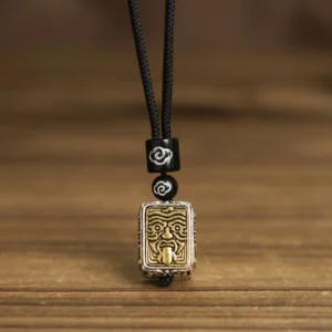 Zakiram tibetan protective deity pendant necklace front display, black woven cord with decorative spacer beads and square relief pendant on wooden surface