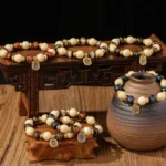 Collection of Tibetan Zakiram wealth goddess bracelets with multiple color variations featuring liuli glass and incense ash porcelain beads on wooden table