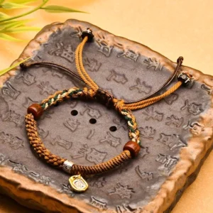 Zakiram goddess of wealth tibetan braided bracelet with wooden beads and metal charm on carved stone tray, flat lay top view