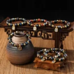 Tibetan Zakiram wealth goddess bracelets collection overhead view with mixed liuli glass beads and gold spacers on wooden display