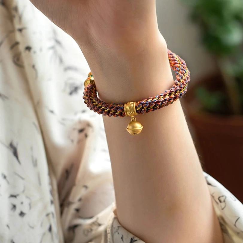 Minimalist zodiac braided bell bracelet on wrist with brown woven rope and gold bell charm
