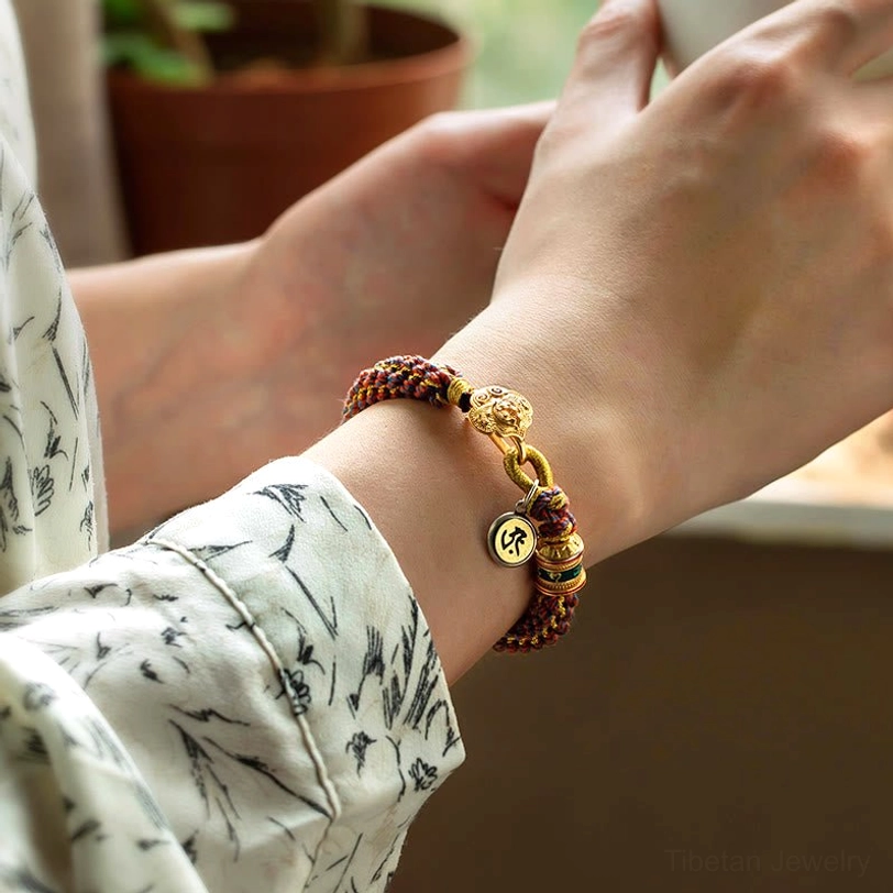 Zodiac luck bracelet worn on wrist with brown mixed braided rope and gold metal charm pendant