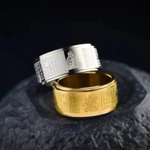 Dual-tone Chinese zodiac natal Buddha spinning ring with Heart Sutra engraving on dark stone surface, showing three-quarter view