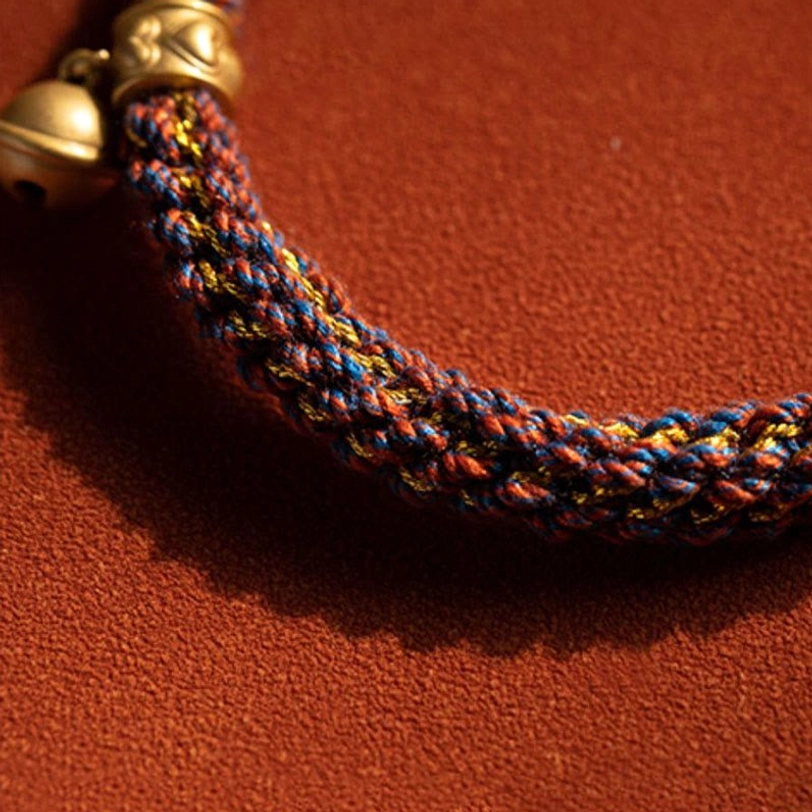 Zodiac braided luck bell bracelet flat lay showing mixed-color woven rope and gold hardware clasp