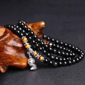 Multi-layer Chinese zodiac mala bracelet with black obsidian beads, tiger eye stones, and silver monkey pendant on dark background