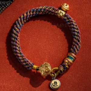 Chinese zodiac natal Buddha braided bracelet with mixed-color woven rope, gold metal charms and Sanskrit pendant, flat lay